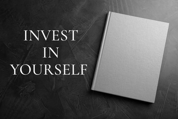 Invest in yourself, affirmation. Book and words on black table, top view