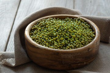 mung beans  (Vigna radiata) , green mung beans in a wooden bowl on an old rustic table