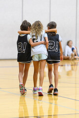 Young child basketball players helping a teammate off of the court after an injury while playing in a game