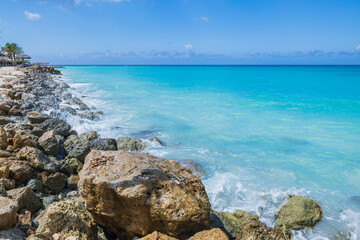 Fototapeta na wymiar Beautiful view of Atlantic Ocean with turquoise water on island of Aruba with incoming wave on rocky shore.