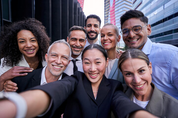 Happy multicultural group of male and female business people taking a selfie together outdoors at workplace. Chinese businesswoman making a photo with her work colleagues.