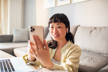 Young Japanese woman using a smart phone in the living room