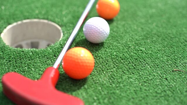 Close-up of miniature golf hole with bat and ball