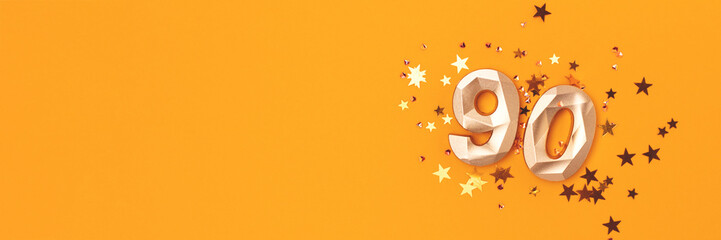 Banner with golden number 90 and stars confetti on a yellow background. Festive glowing compisition...