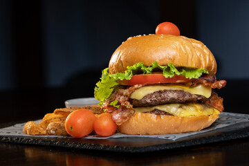 Super Hamburguesa grande con tomates y papas fritas a un lado