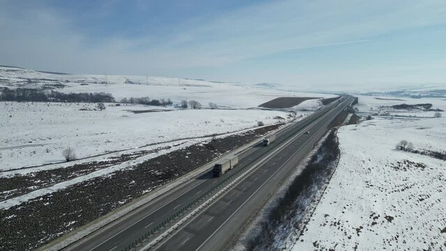 High-angle shot of traffic on the highway in winter, snowy fields around