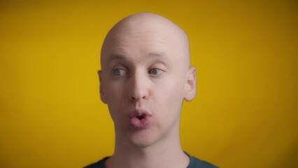 Man with blue eyes and bright skin looking awkward and embarrassed on a yellow background, Real time. - Powered by Adobe