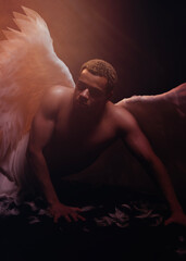 Young strong angel with white wings from heaven. Angel with muscular body. Sensual man