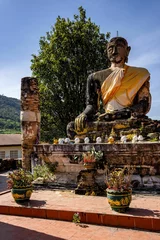 Papier Peint photo autocollant Monument historique Vertical shot of an ancient and worn statue of Buddha in Wat Phiawat, Xiangkhouang, Laos
