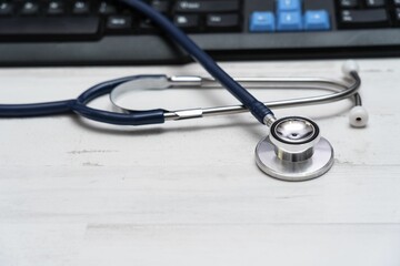 Stethoscope on white desk near a keyboard, healthcare concept