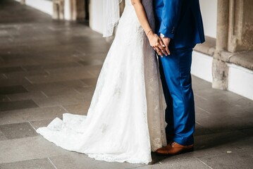 Plakat bride and groom pose in an archway near the building's walls