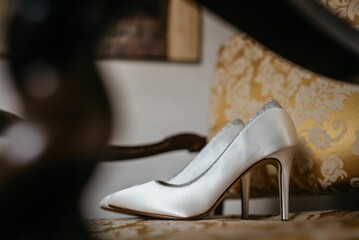 Bridal wedding shoes sitting on a chair with a gold damask patterned fabric
