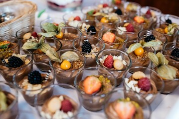 Collection of small desserts containing various fruits and nuts arranged in glass cups