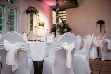 an event venue with white chairs and decorated tables set up for a formal function