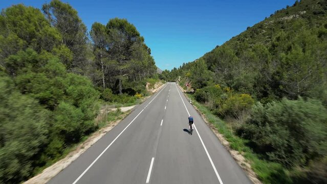 Drone shot.Cyclist preparing to triathlon competition on time trial bicycle.Hard sport workout.Fit male cyclist wearing sportswear and aero helmet.Spain