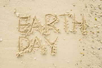 The word EARTH DAY is writting on the sand. drawing on the sand. writing with sands on the beach.
