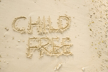 The word CHILD FREE is writting on the sand. drawing on the sand. writing with sands on the beach.