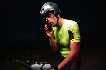 A triathlete using a smartphone while taking a break from a hard night's cycling training