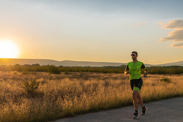 Triathlete in professional gear running early in the morning, preparing for a marathon, dedication...