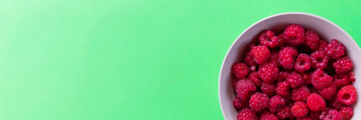 Red raspberry berry in plate on green table. Fruit berries background. Summer food.Diet vitamin and vegan food, organic, natural and healthy snack.copy space. web banner