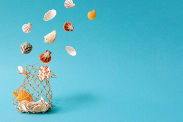 Seashells floating from a net against light blue backgorund. Summer beach vacation concept.