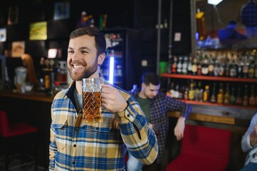 Night in bar. Portrait of cheerful men drinking beer at the bar