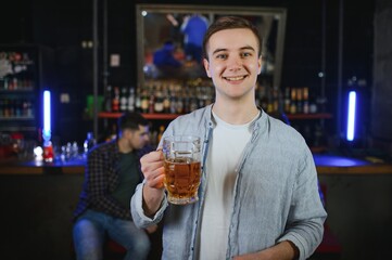 Handsome bearded man drinking beer at the bar counter in pub