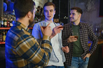 Obraz premium male friends spending time together in bar and having fun. Bearded men smiling, looking at each other and communicating. Men holding crystal glasses of whisky or scotch.