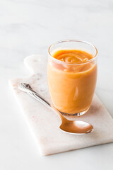 Freshly made creamy salted caramel dessert topping in a small glass.