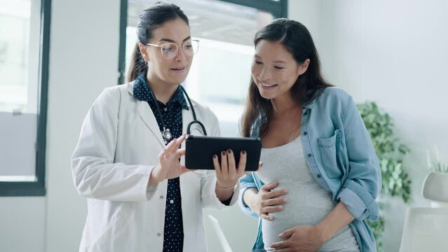 Video of female gynecologist doctor showing to pregnant woman ultrasound scan baby with digital tablet in medical consultation.