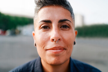 Authentic portrait of gay lesbian woman smiling on camera outdoor - Lgbt nonbinary people concept - Main focus on eyes