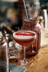 the customer takes a delicious pink freshly prepared raspberry milk punch cocktail from the bar