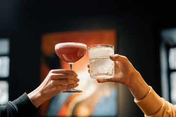 Close up of two people cheering cocktails in a bar or disco club drinks and cocktails concept