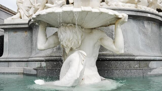 Footage of a male mermaid statue as part of the Pallas Athena Fountain represents strength.