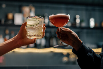 Close up of two people cheering cocktails in a bar or disco club drinks and cocktails concept
