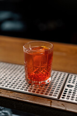 A close-up of the ready-made delicious alcoholic cocktail Negroni is standing on the bar and waiting for the guest