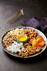 Assorted nuts and dried fruits in oriental style on a platter - dried apricots, cashews,...