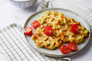 Snack waffles with bacon, cheddar cheese, spinach, sauce and cherry tomatoes on light background