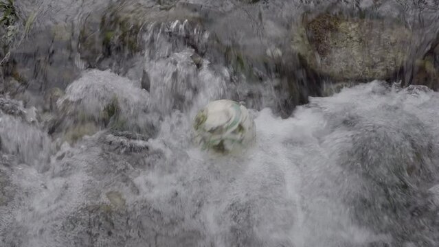 Un pallone da calcio di cuoio caduto nel torrente viene cullato dall'acqua e diventa un elemento inquinante