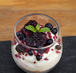 Delicious dessert. Closeup view of a trifle cup with yoghurt, white chocolate cream, cereal and red berries.