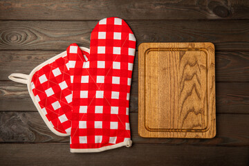 Wooden kitchen utensils, cutting board, potholder and glove on the table, top view. Kitchen Mitten...