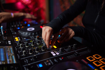 An expert adjusting audio mixing console with white blank screen laptop on control desk.