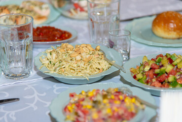 Different salads on white plates staying on banquet table. Sliced cabbage, corn, tomato, pepper, cucumber, healthy vegetarian dishes. Selective focus