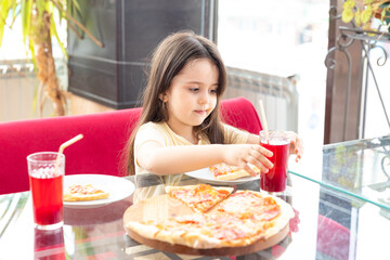 Cute little girl eating cheese pizza for lunch close up. Smile and enjoy sunny day and yummy meal in a pizzeria