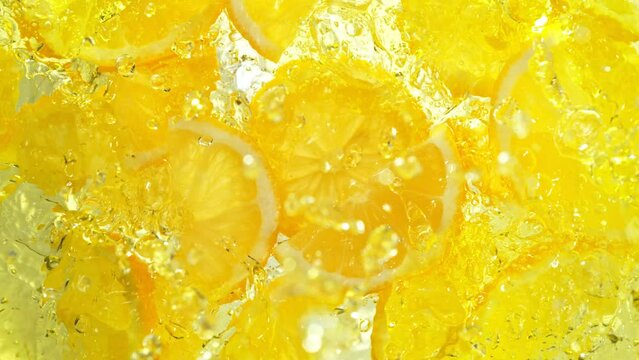 Super Slow Motion Shot of Fresh Lemon Slices Falling into Lemonade Whirl at 1000 fps.