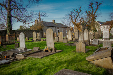 Fototapeta na wymiar Graveyard or cemetery in Drogheda in early morning hours with sun just rising up. Low profile photo with grass in the morning.