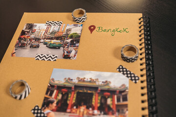 Handmade kraft album with travel photos and washi tape with the word Bangkok written next to a red location symbol.
