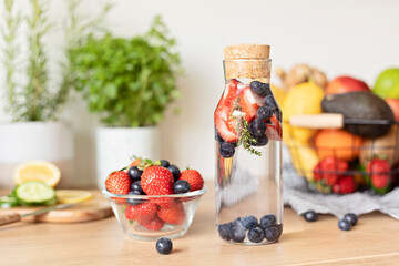Infused  water with strawberry and blueberries in glass bottle on wooden table. Diet, detox, healthy eating, weight loss concept