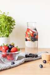 Infused  water with strawberry and blueberries in glass bottle on wooden table. Diet, detox, healthy eating, weight loss concept