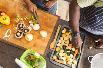 Foto op Plexiglas Senior african american couple wearing aprons and preparing vegetables in kitchen © wavebreak3